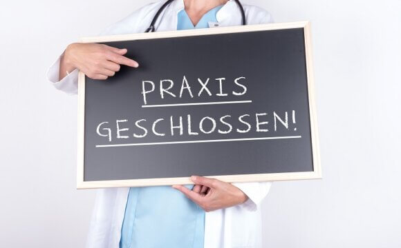 Arzt mit Schild Praxis geschlossen